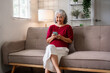 © snowing12 - Asian older woman uses smartphone relaxing on comfortable sofa in home connecting with digital technology for modern communication and leisure