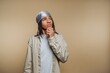 © bodnarphoto - Young man with braids pondering thoughts against a neutral background in a relaxed setting