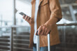 © oatawa - Close-up of Asian male traveler’s hand holding smartphone and suitcase handle at airport terminal – modern travel lifestyle, mobile connectivity, trip preparation journey