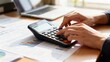 © misu - Person using a calculator for financial calculations at a desk.
