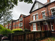 Red brick terrace houses along a tree lined street in Manchester UK with scaffolding