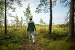 © DimaBerlin - Rearview of hiker woman with basket forage mushrooms in pine forest on trail reaching sunny edge. Forest foraging, outdoor adventure and wanderlust, fungi collecting, solo exploration hobby