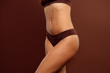 Young woman in brown lingerie posing with confidence on a brown background highlighting natural beauty and diversity
