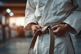 Practicing martial arts in a training studio while tying a brown belt during an evening session
