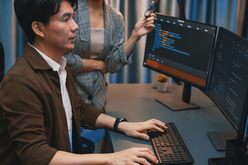 IT developers discussing with point to intelligent website development coder system running data online two screens information technology at neon light room at modern office. Infobahn.