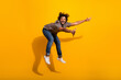© deagreez - Energetic young man in a leopard print shirt jumps playfully against a vibrant yellow background, showcasing fashion and enthusiasm