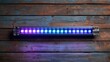© PUTRABATARA - Long, horizontal light bar with numerous LEDs,  in shades of purple and blue, mounted on a weathered wooden plank wall