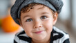 © ArtShop - Young boy wearing a black and white striped shirt and a black hat smiling in a cozy indoor setting for Halloween