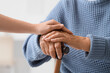 © Pixel-Shot - Senior woman with stick and granddaughter holding hands in clinic, closeup