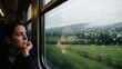 © AudaX - A pensive woman rests her chin on her hand while looking out a rainy train window.