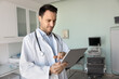 © fizkes - Busy male doctor using tablet in office with ultrasound equipment