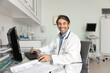 © fizkes - Portrait cheerful male doctor sitting at table looking at camera