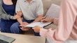 © STBSTD - Insurance professional consults Asian couple at home discusses health policy document signing financial future planning comfortable residential meeting
