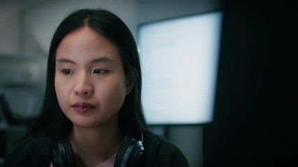 Young Asian Female Tech Developer and Computer Programmer using desktop computer typing on keyboard, writing code, developing software application and reviewing code sit at desk in modern Tech office.