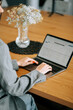 © Darius - Person working on laptop at wooden table with vase of flowers during daytime