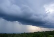 © RIFAN - Dramatic Storm Clouds Overtake Lush Green Forest Landscape with Sunbeams Breaking Through