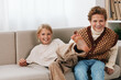 © SHOTPRIME STUDIO - Authentic candid scene showing siblings at home after school, engaged in a playful moment on a cozy sofa with warm light and relaxed everyday lifestyle.