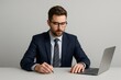 © Татьяна Евдокимова - Young businessman sitting at a desk, working intently on a laptop while taking notes, dressed in a sharp suit and tie