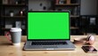 © Peacock - An Open Laptop with a Chroma Key Green Screen Set Up on a Wooden Desk in a Contemporary Office Environment.