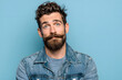© Daniel - Hombre español, joven, de 30 años, con gran bigote y barba, posando para la cámara sobre fondo de estudio azul pastel. Concepto salud masculina, movoimiento de marzo
