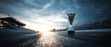 Trophy cup on the asphalt race track with a blurred background of a sunset sky. 