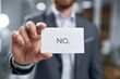 © Best Wishes Art - An Individual Holding a Card with the Word 'NO' in a Professional Setting, Representing Rejection or Disapproval in Business Contexts