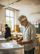 © Atlantis - Senior man inserting ballot paper into box at polling station