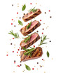 © NAStudio - Delicious grilled steak slices with herbs and peppercorns flying, perfect for food blogs and culinary designs, mouthwatering delight