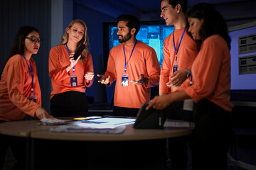 A diverse team of app developers and product designers collaborates on a new mobile device. They are brainstorming ideas for the phone's software and hardware features.
