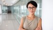 © Ulia_photo - Elegant Asian corporate manager with short hair and glasses, 35 years old, confident expression, standing in bright office interior.