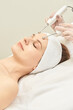 © elenavolf - Young caucasian female receiving facial microcurrent therapy in spa setting for skin rejuvenation.