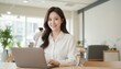 © Yka - 明るいラウンジでノートPCと微笑む女性