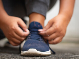  young asian women use their hands to tie their shoes jogging in morning workout at the city