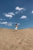 Woman Running on Sand Dunes Under Blue Sky