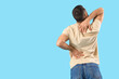 © Pixel-Shot - Young man suffering from back pain on blue background