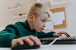 © looking2thesky - A boy with hearing aids focuses intently while playing a game on his laptop, showcasing modern adaptive technology and inclusive digital entertainment for children with hearing disabilities