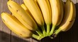© FAJAR - Ripe yellow bananas arranged on a rustic wooden surface, bathed in sunlight.