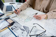 © RomanR - Professional female interior designer working with house sketch plan in office, workplace