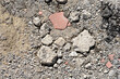 © nahhan - A close-up of a scattered, rough surface with broken pieces of concrete and brick, gravel, and dirt