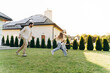 © Maria Vitkovska - Happy family playing and running together in the backyard of their modern house