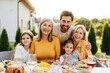 © Maria Vitkovska - Happy family enjoying outdoor meal in backyard hugging together looking at camera