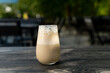 © RooM The Agency - Close-up of an Iced coffee latte with frothy foam on a wooden garden table