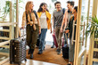 © Davide Angelini - Young group of tourists with suitcases arriving at youth hostel guest house - Happy friends enjoying summer vacation together - Millenial people doing check-in at hotel lobby - Summertime holidays