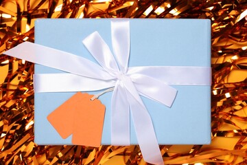 Wall Mural - Gift box with blank tags and streamers on orange background, flat lay