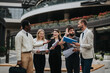 © qunica.com - A group of business professionals gathers outdoors in a modern city setting, discussing work while holding documents, exuding collaboration and professionalism.
