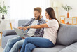 © Studio Romantic - Happy husband and wife at home resting on sofa holdinng laptop to choose goods online, young family couple using pc, discussing food order, flat renovation, planning trip vacation, planning wedding
