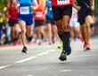 © Laura - Runners in a race or community run / marathon / 5k showing legs and shoes wearing bib numbers.