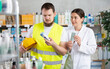 © JackF - Male construction worker holding a package of cooling ointment for muscles and joints, he consults with a female pharmacist about choosing an ointment