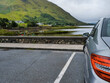 © mark_gusev - Car parked with view on mountains and Leenaun village and Killary fjord and harbor. Popular tourist area in Connemara, Ireland. Cloudy sky. Travel and tourism. Irish landscape.