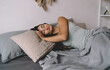© BullRun - Brunette woman enjoying restful sleep at home, arms folded under pillow, gentle smile on face, representing emotional security, slow living and balance in everyday routine.